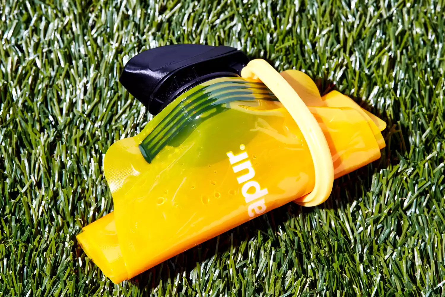 A Vapur Solid Flex Collapsible Water Bottle lying on grass